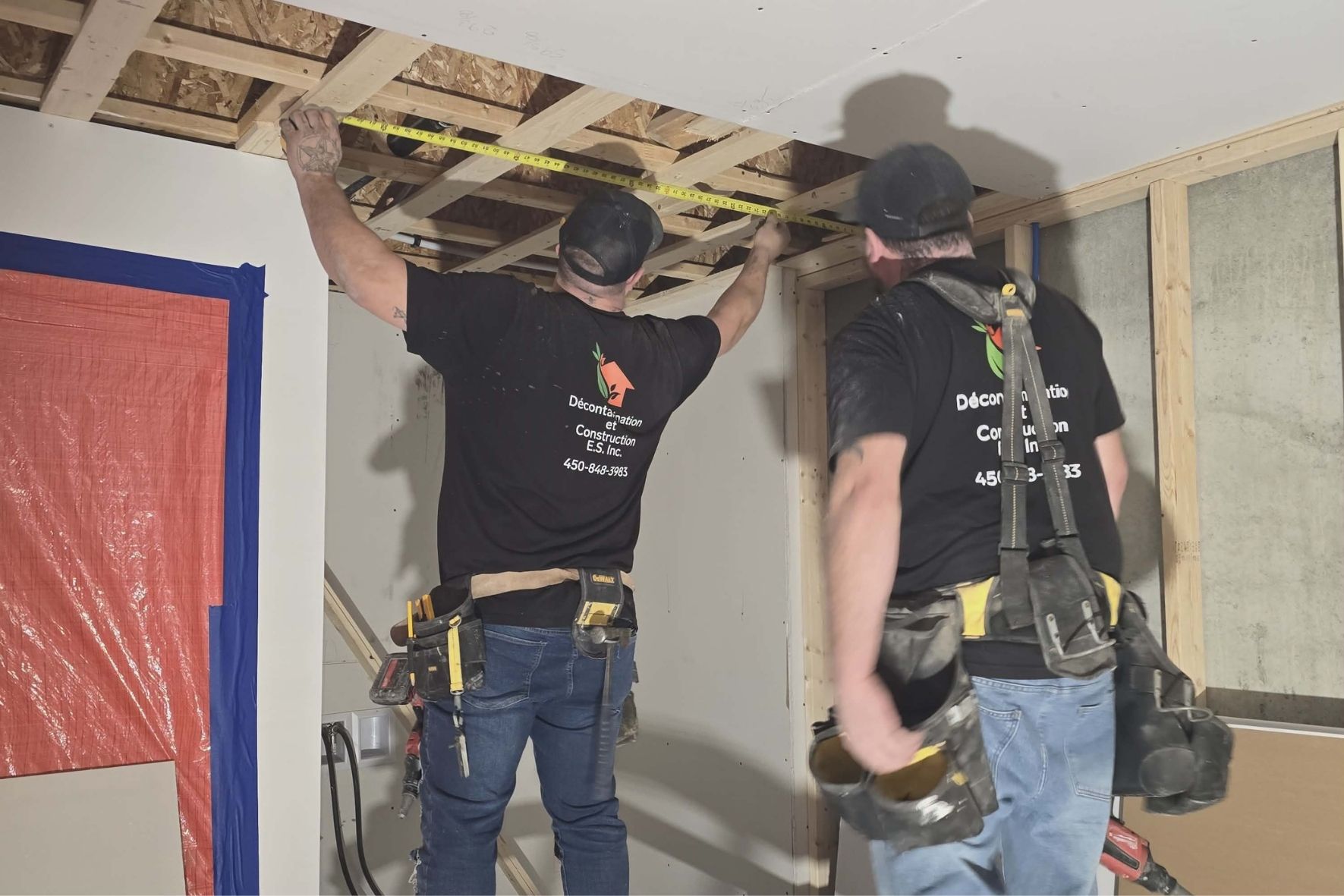 Deux travailleurs mesurant une structure intérieure en bois dans un espace rénové  à L`Île-Bizard